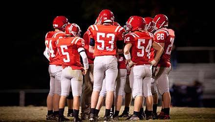 photo of a football team on the field in a huddle