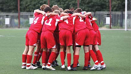 photo of soccer team in an arm-in-arm circle